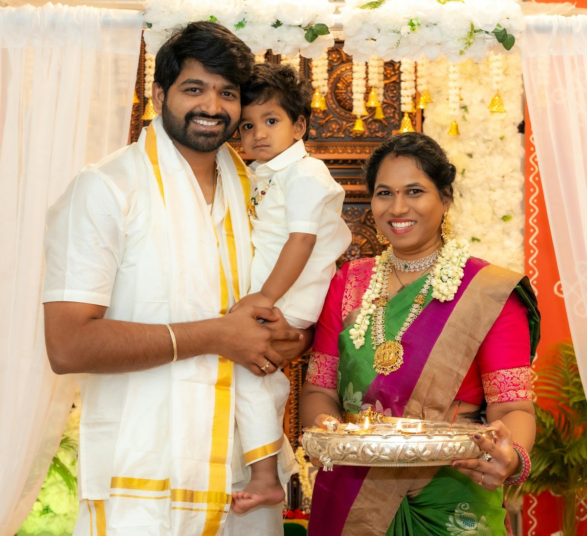 A couple in traditional Indian dress, the man holding a small child