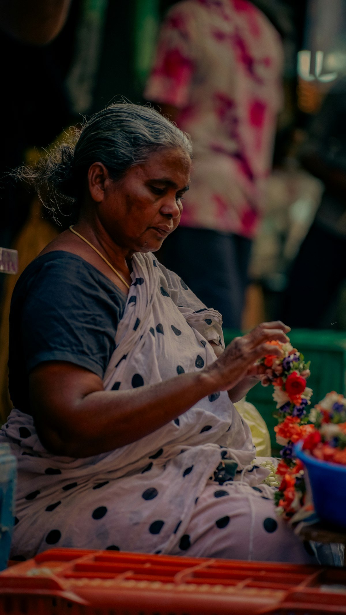 A woman making flower garlands by hand