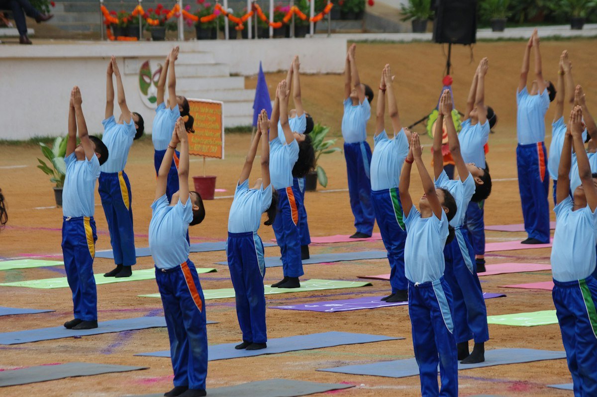A large group exercising in rows on mats outdoors