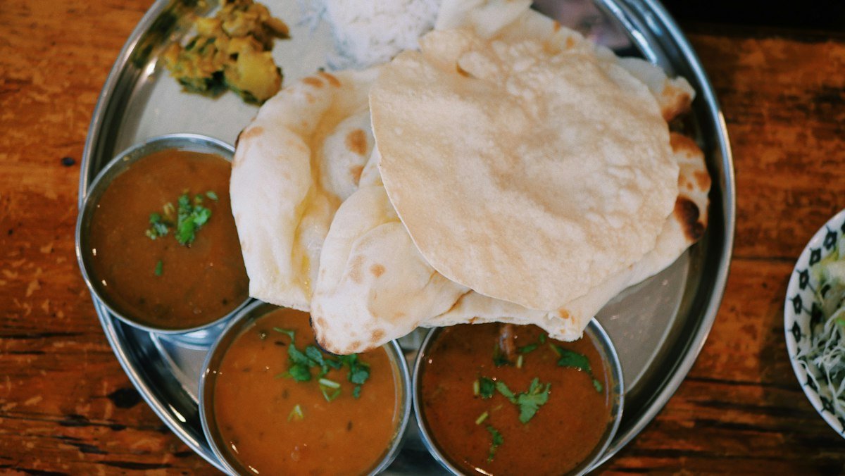 Rotis with bowls of dal in a steel plate on a wooden table