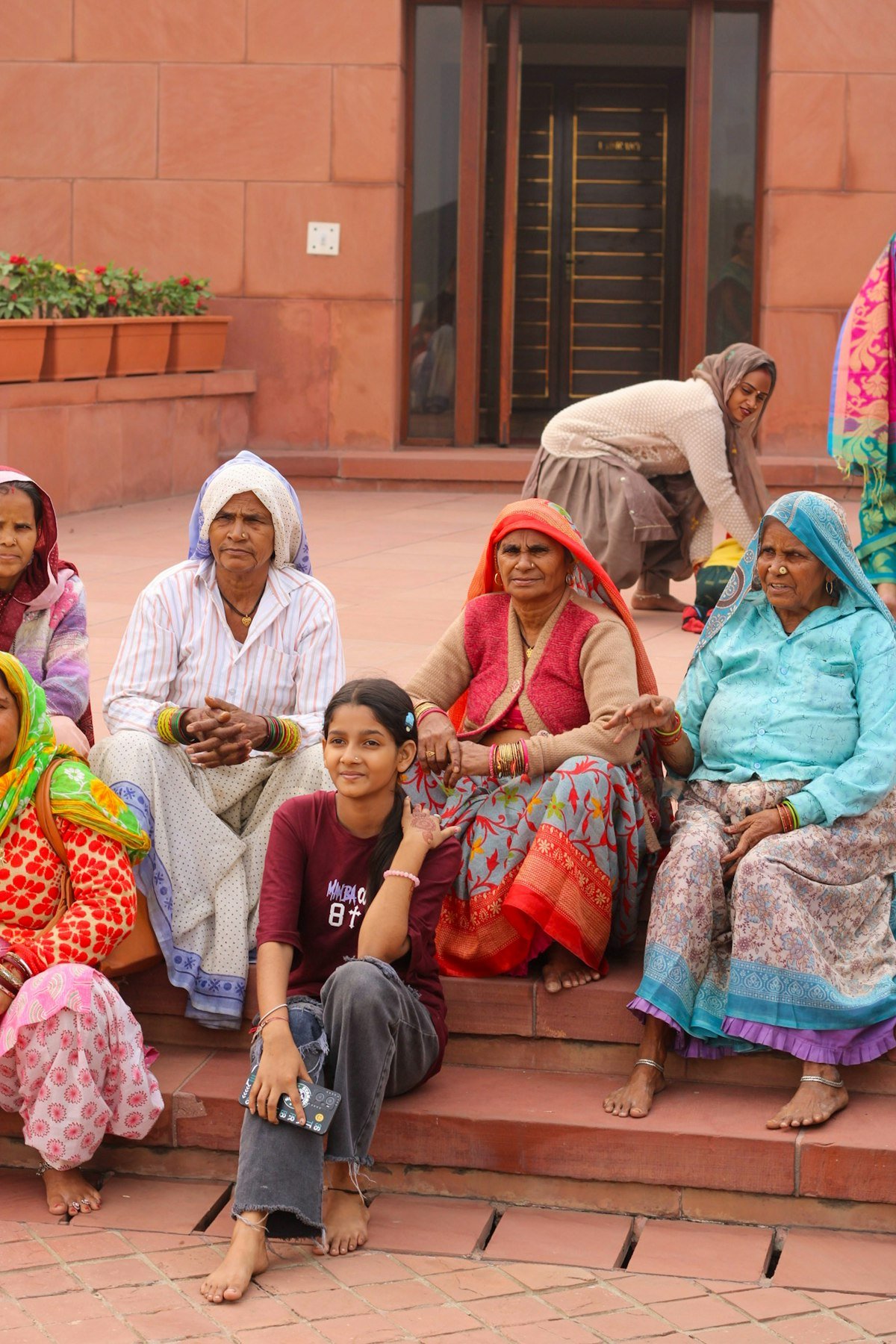 A group of women, including an elderly woman and a girl, sitting together outdoors